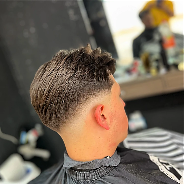 Fade con volumen: degradado bajo en la nuca y textura larga arriba, visto de perfil